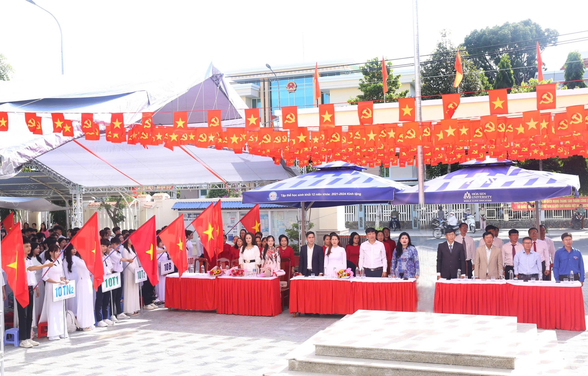 Các đại biểu và thầy, trò Trường THPT Nguyễn Trãi thực hiện nghi thức chào cờ.